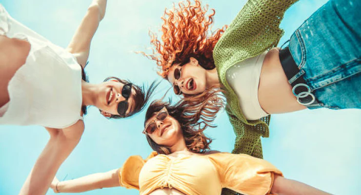 Three people lying on their backs with a clear blue sky above them